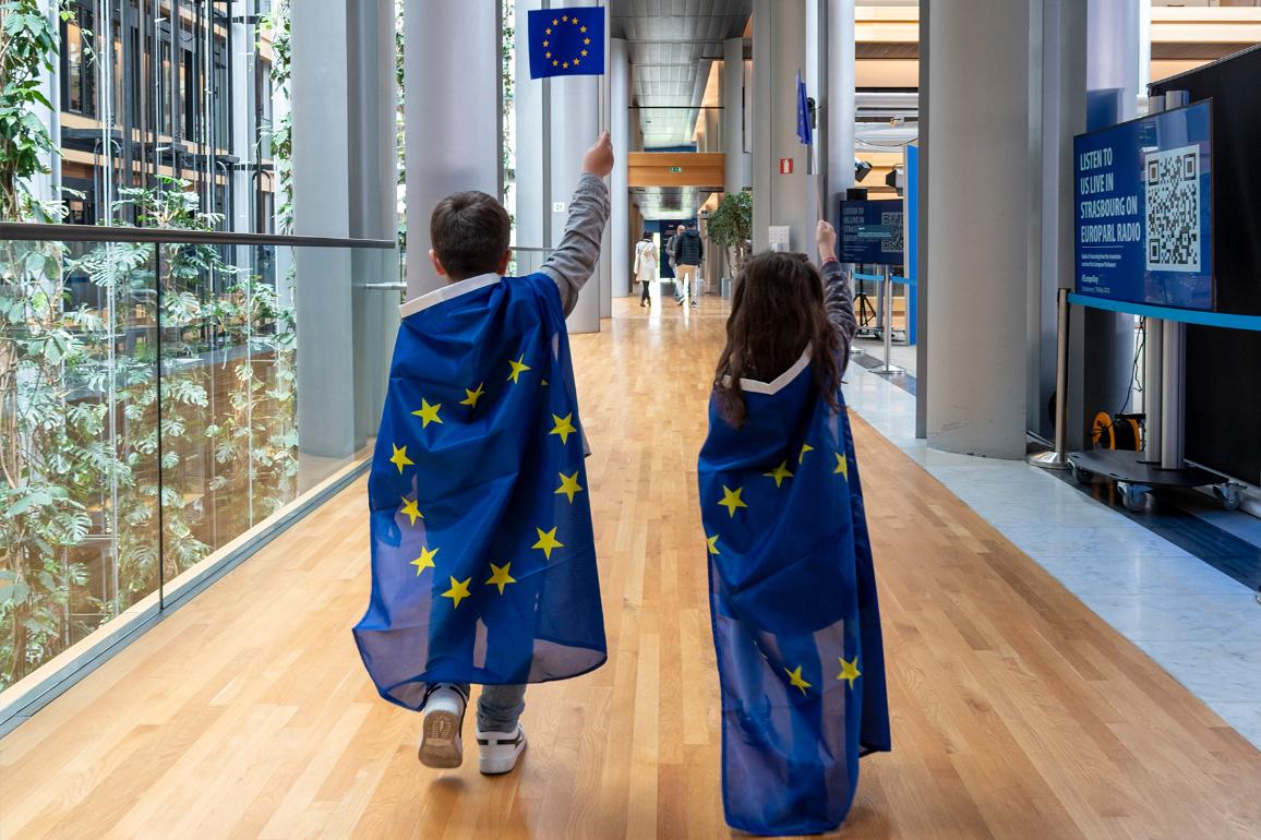 Two children wear a European Union flag in the European Parliament building in Strasbourg, France