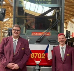 Zwei Auszubildende der DVG stehen vor einer Straßenbahn im Straßenbahndepot Prag