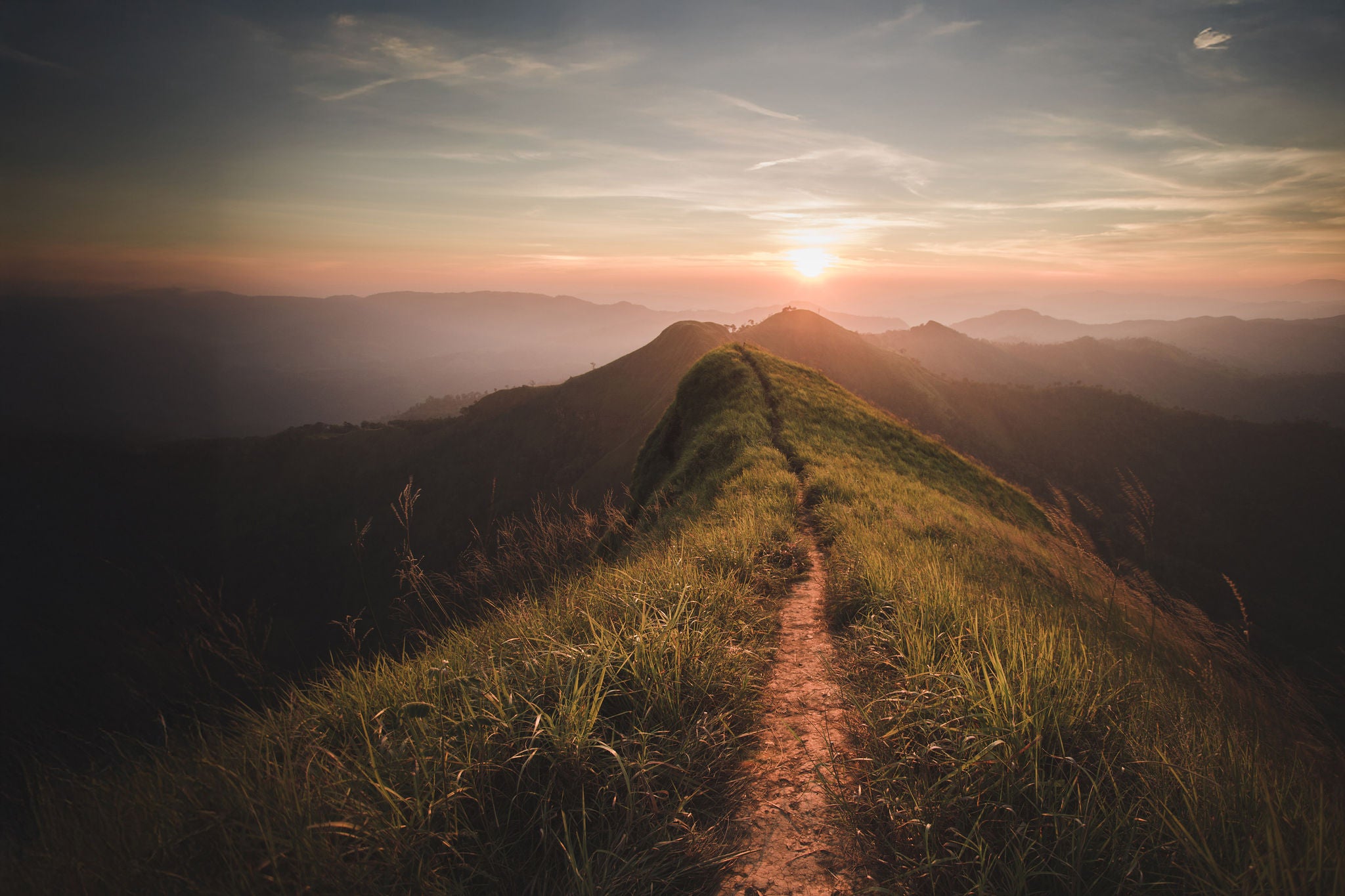 Pathway along the top ridge of a hill with sunset in distance