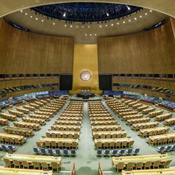 This photo shows an unoccupied United Nations General Assembly room, designed in sage green and gold.