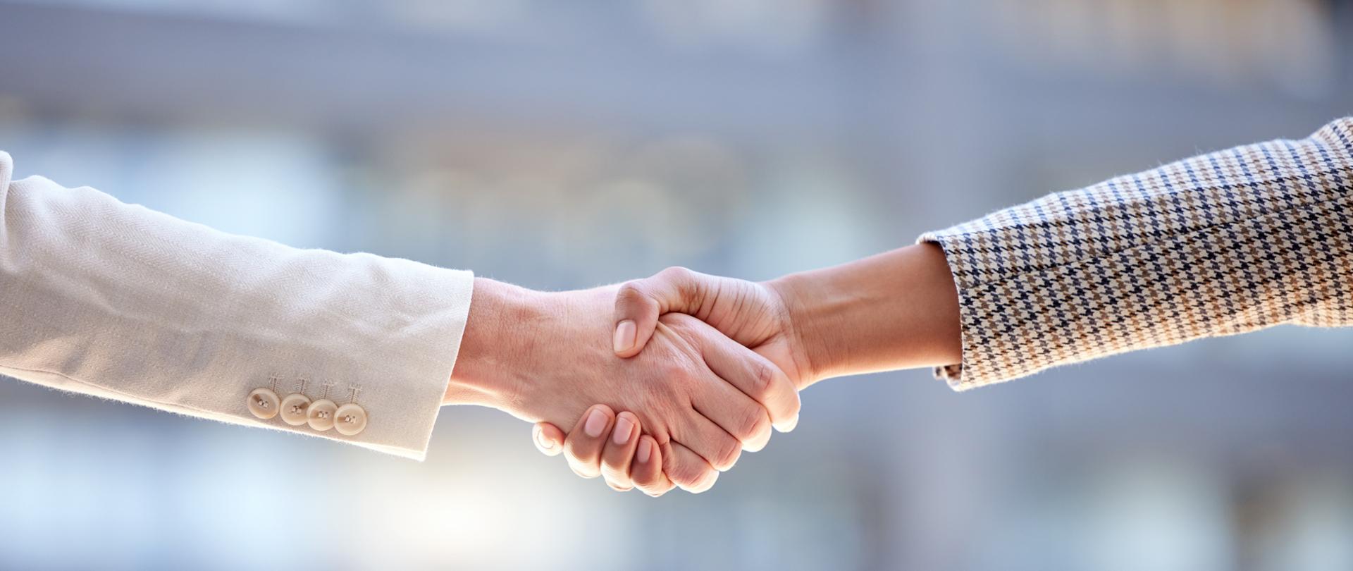 Shot of two unrecognizable businesspeople shaking hands against a city background.