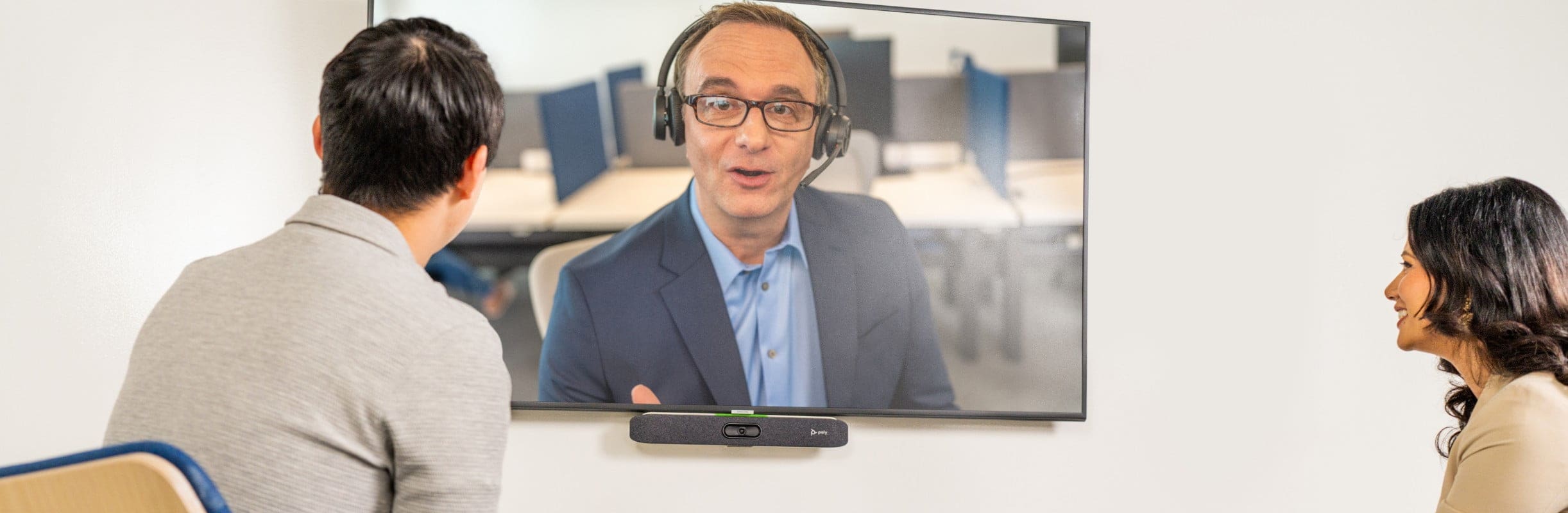 Two people in a small meeting room using Poly Studio X30 video bar for a video call 