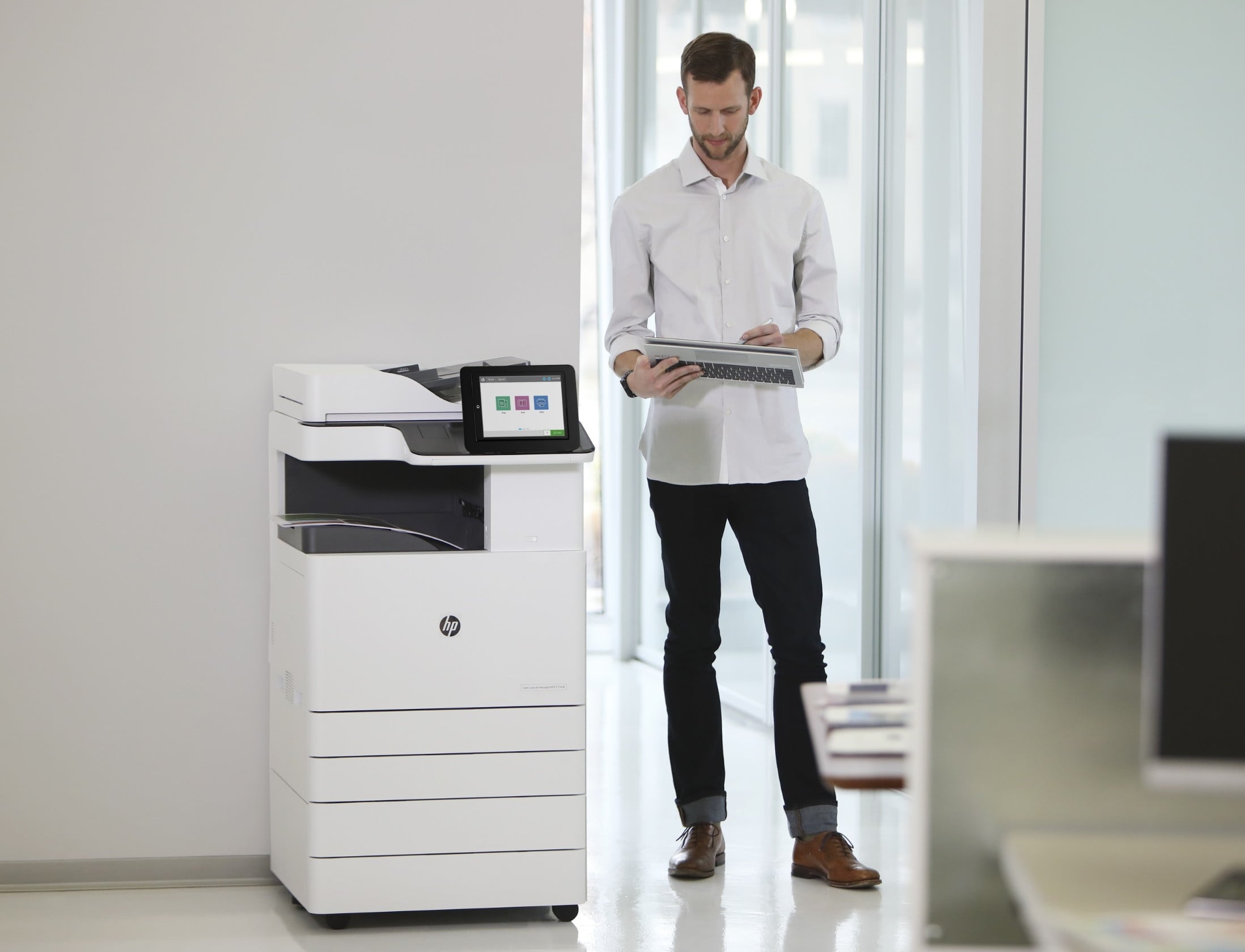 Man står vid en HP LaserJet Enterprise-skrivare och tittar på utskrivna dokument