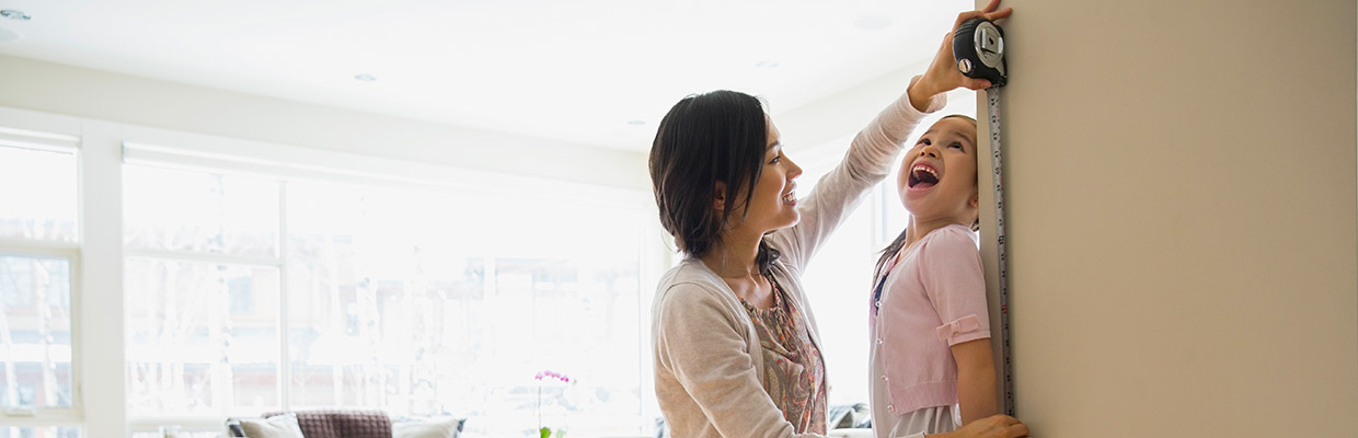 A mother is measuring her daughter's height; image used for HSBC Singapore Time Deposit Account