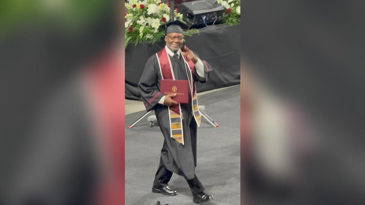 Man with cap and gown holding diploma