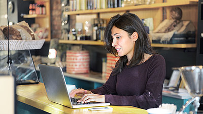 Lady working with laptop at bar counter in cafe