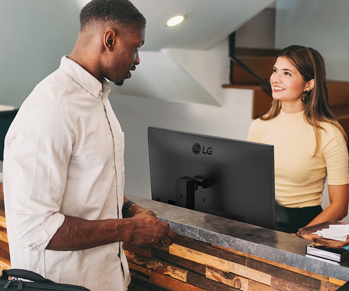 A female receptionist is talking to a man at the front desk.	