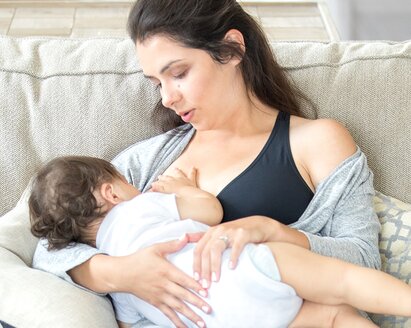 A mother breastfeeding her baby while wearing a Medela maternity bra.