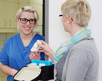 Zwei Frauen in einem Krankenhaus mit Muttermilch in Vorratsflaschen in einer Medela Kühltasche.