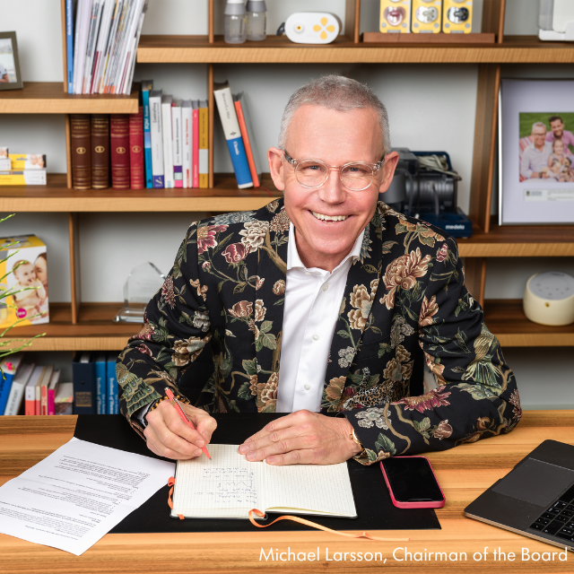 Foto von Michael Larsson bei der Unterzeichnung eines Dokuments, während er am Schreibtisch sitzt.