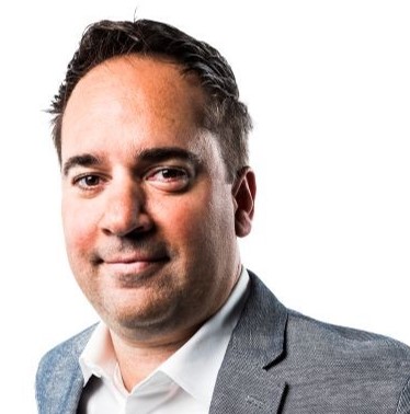 a man wearing a suit and tie smiling at the camera