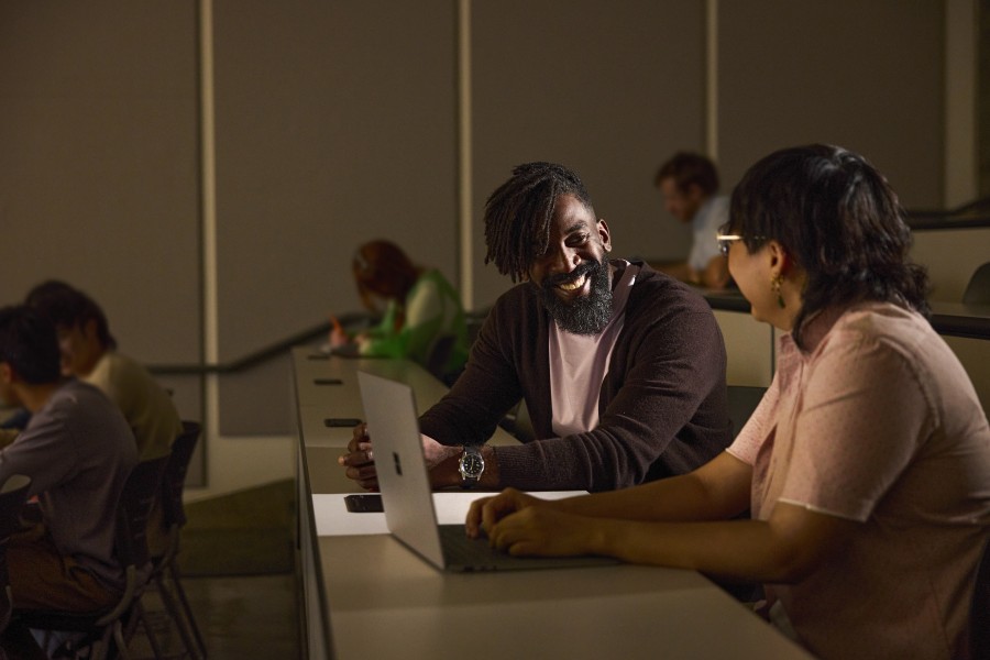 Decorative. A professor and student chatting in a college auditorium-style class.