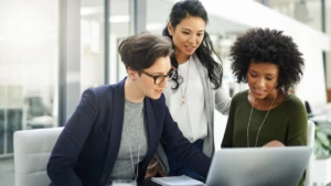 Three coworkers collaborating around a computer