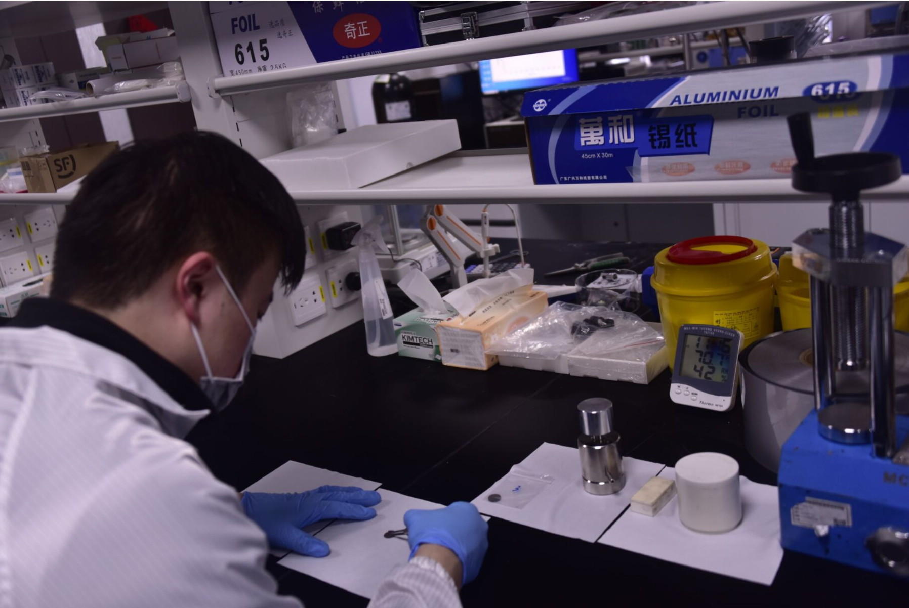 A photo that shows a scientist in a laboratory working at a bench and holding a small sample with tweezers. 