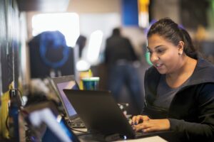 Adult woman working on multiple laptops.