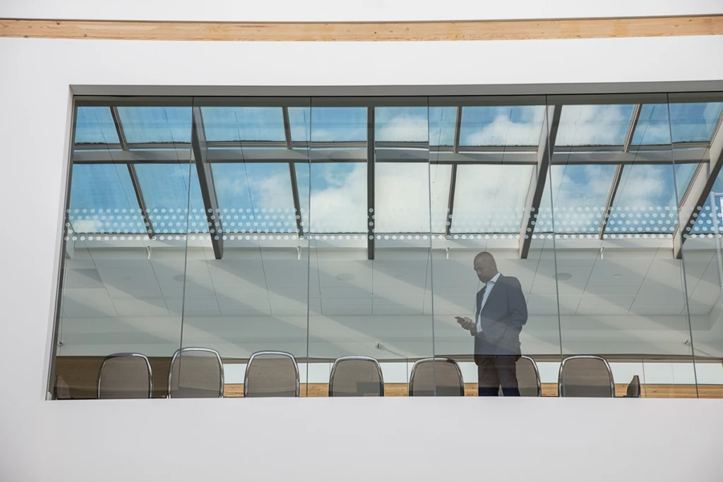 Photo of a man in a meeting room using phone.