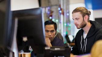 Two male engineers sitting in front of a computer screen.