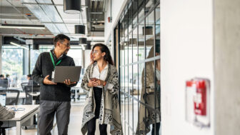 Coworkers discuss business while walking through a modern office