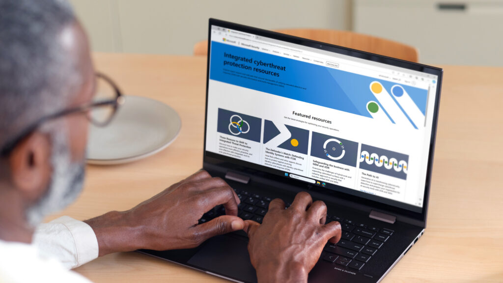 Person typing on laptop with Microsoft cyberthreat protection screen
