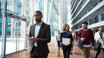 Photo of business professionals in foyer walking, chatting, holding deivces