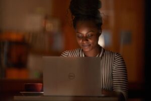 Windows photography of a young adult female inside working on a laptop.