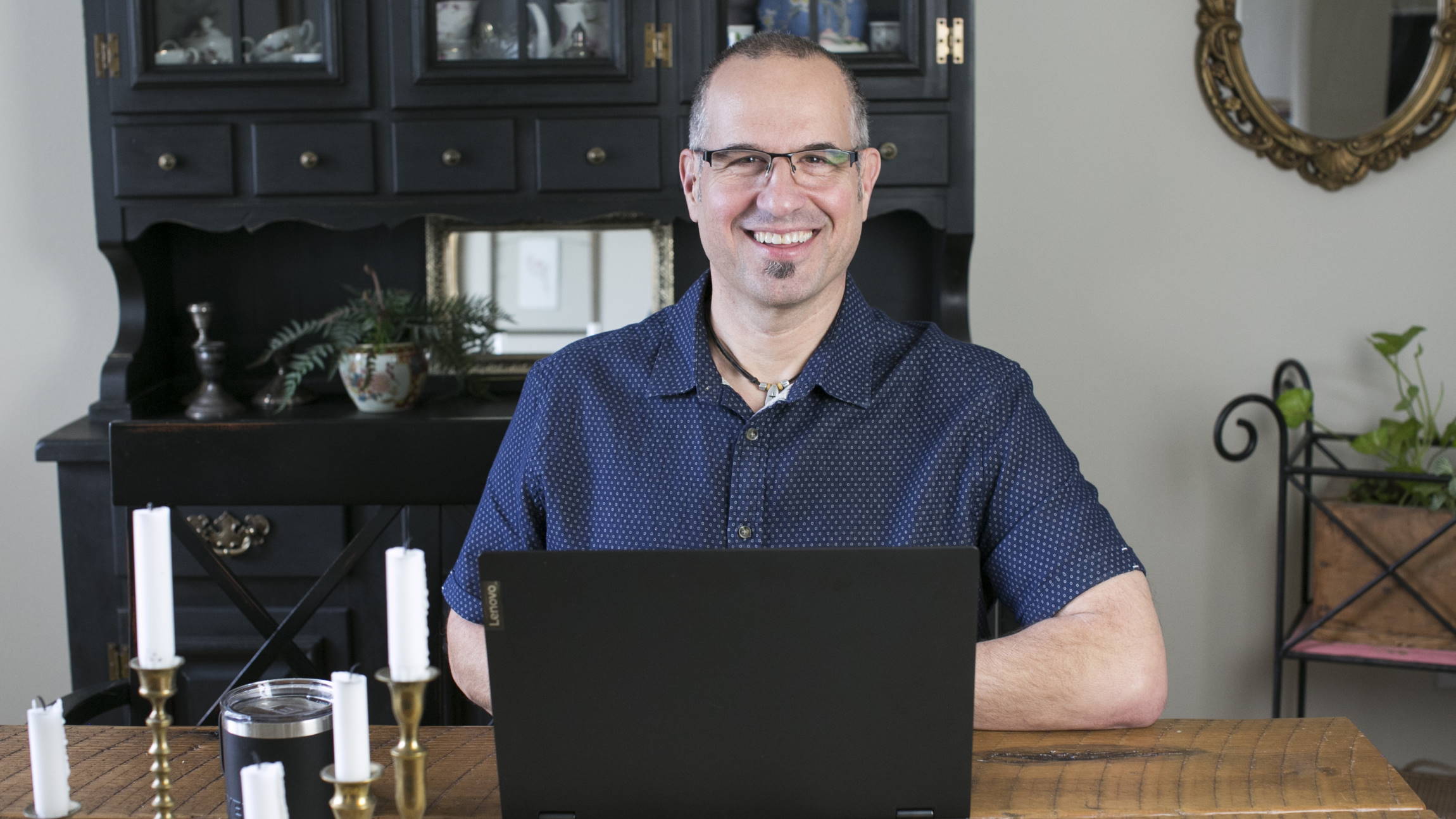 Jerry Newell, wearing headphones, smiles at the camera as he works at home.