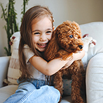 Smiling child hugging small dog.