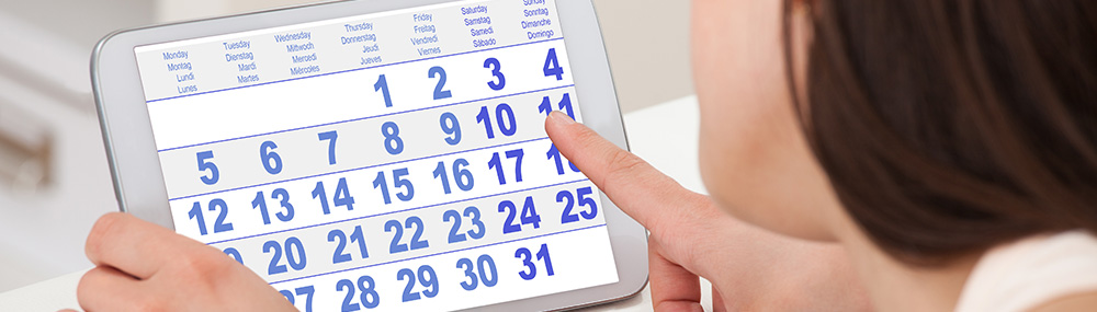 A woman counting days on a monthly calendar on a tablet computer.