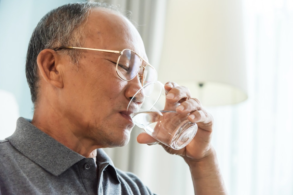 Un hombre bebe un vaso de agua.