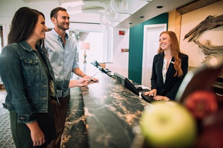 Woman Greets Guests in Hotel Lobby