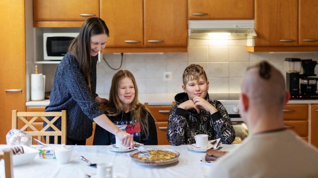 Kaksi teini-ikäistä kahden aikuisen kanssa kahvipöydässä.