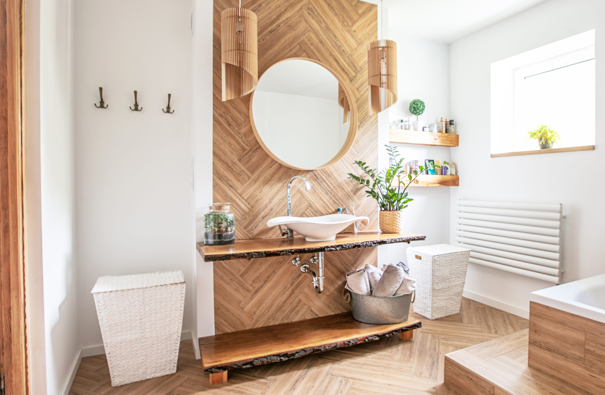 white,sink,on,wood,counter,with,a,round,mirror,hanging