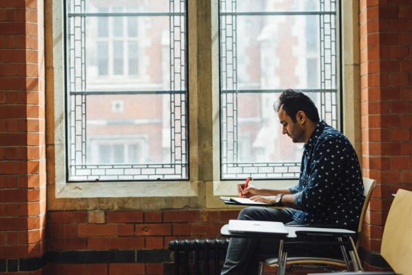 Male student writing in room in Graduate School