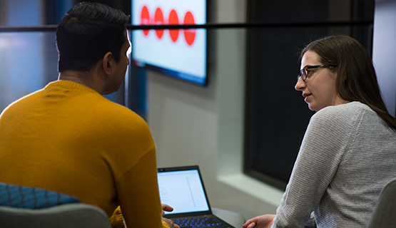 2 people sitting around a computer talking new markets