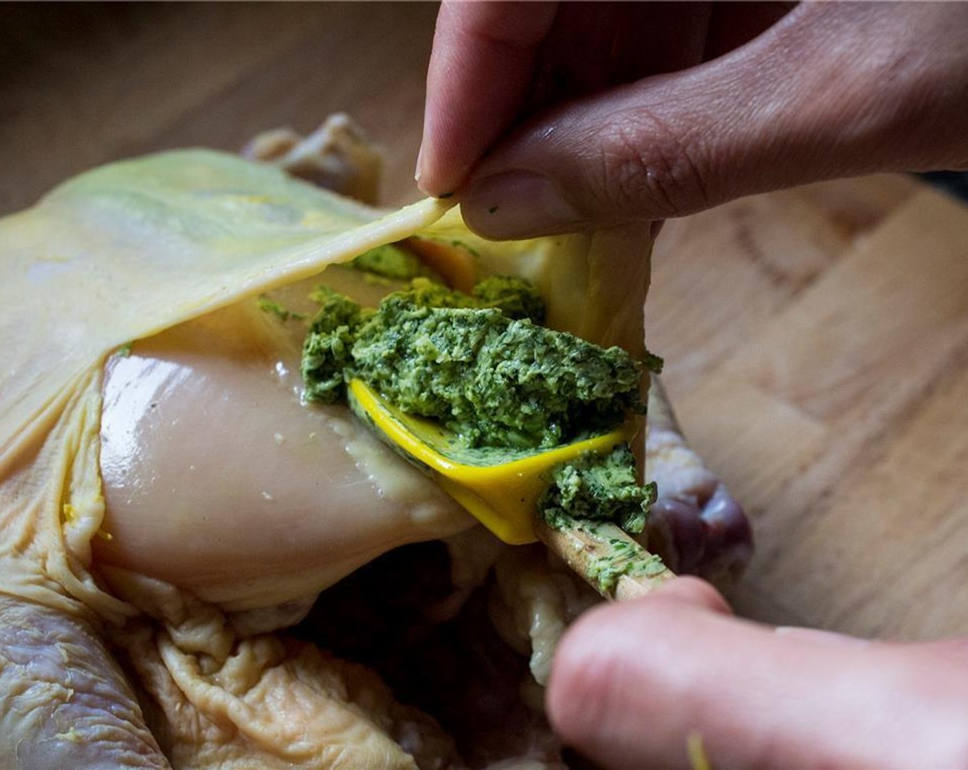 step 4 Using your fingers, carefully separate the skin from the breasts. Place a tablespoon of the herb-butter mixture over the breasts and rub to spread.