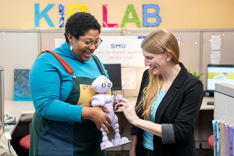 Two education researchers work with a robot toy in the SMU KID Lab