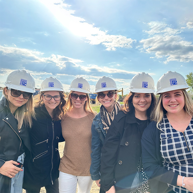 Faculty and students wear hard hats while visiting a field site