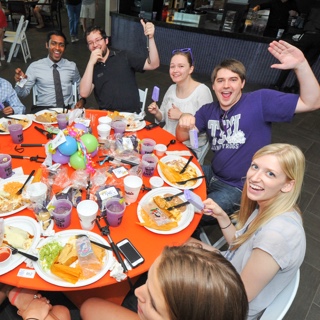 A group of TCU students raise their celebratory purple margaritas at a festive round table