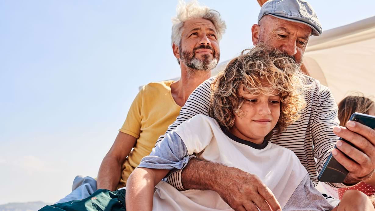 Bild zur Lernreise Urlaub und Freizeit, 2 Männer und Kind mit Smartphone