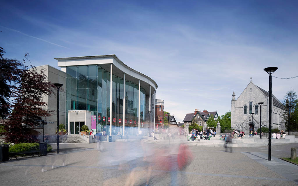 A image of the UCC Student Centre with students walking across the main campus