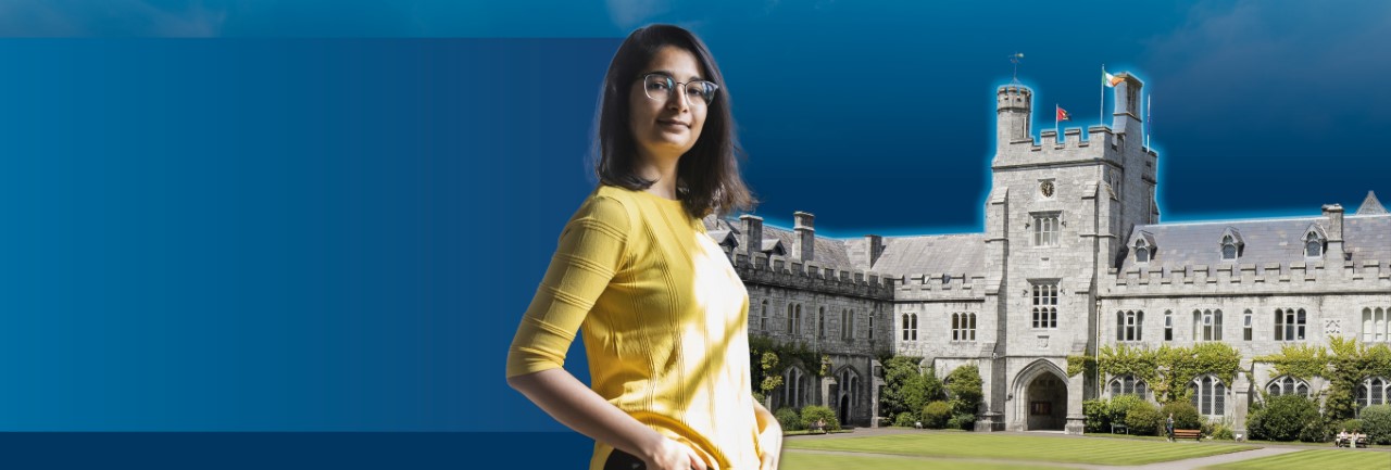 Girl with shoulder length dark hair  in a yellow cardigan turned towards the camera. Standing against a blue background and UCC Campus Quad.