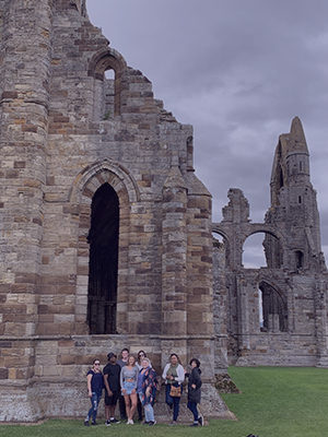 far away shot of student group standing in front of a castle