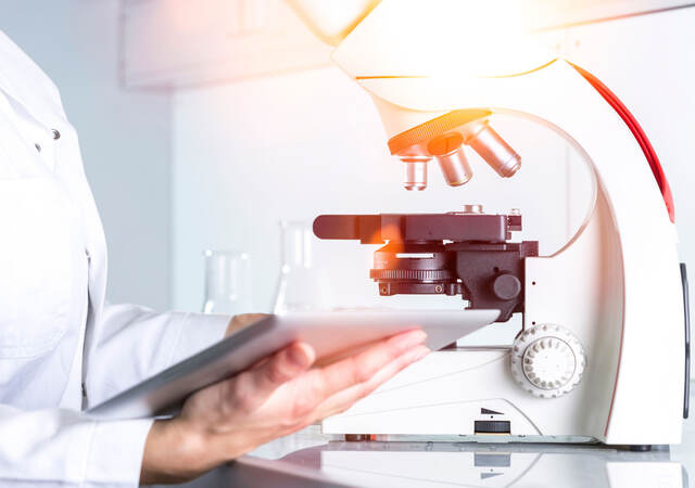 Scientist reviewing notes next to a microscope