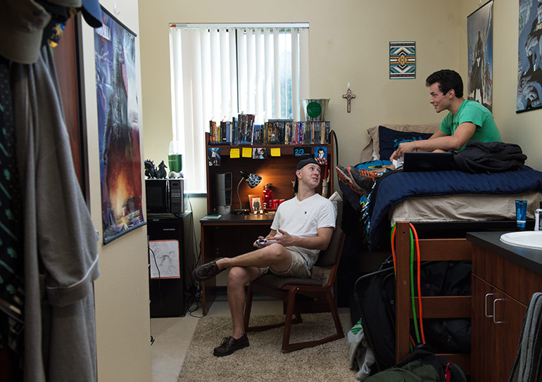 Two students in a well-decorated dorm room.