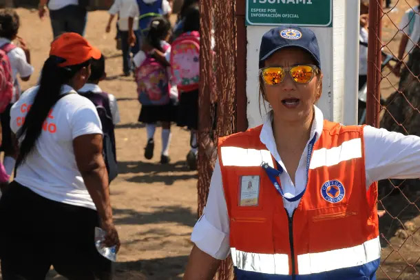 Une femme en gilet de sécurité dirige la foule