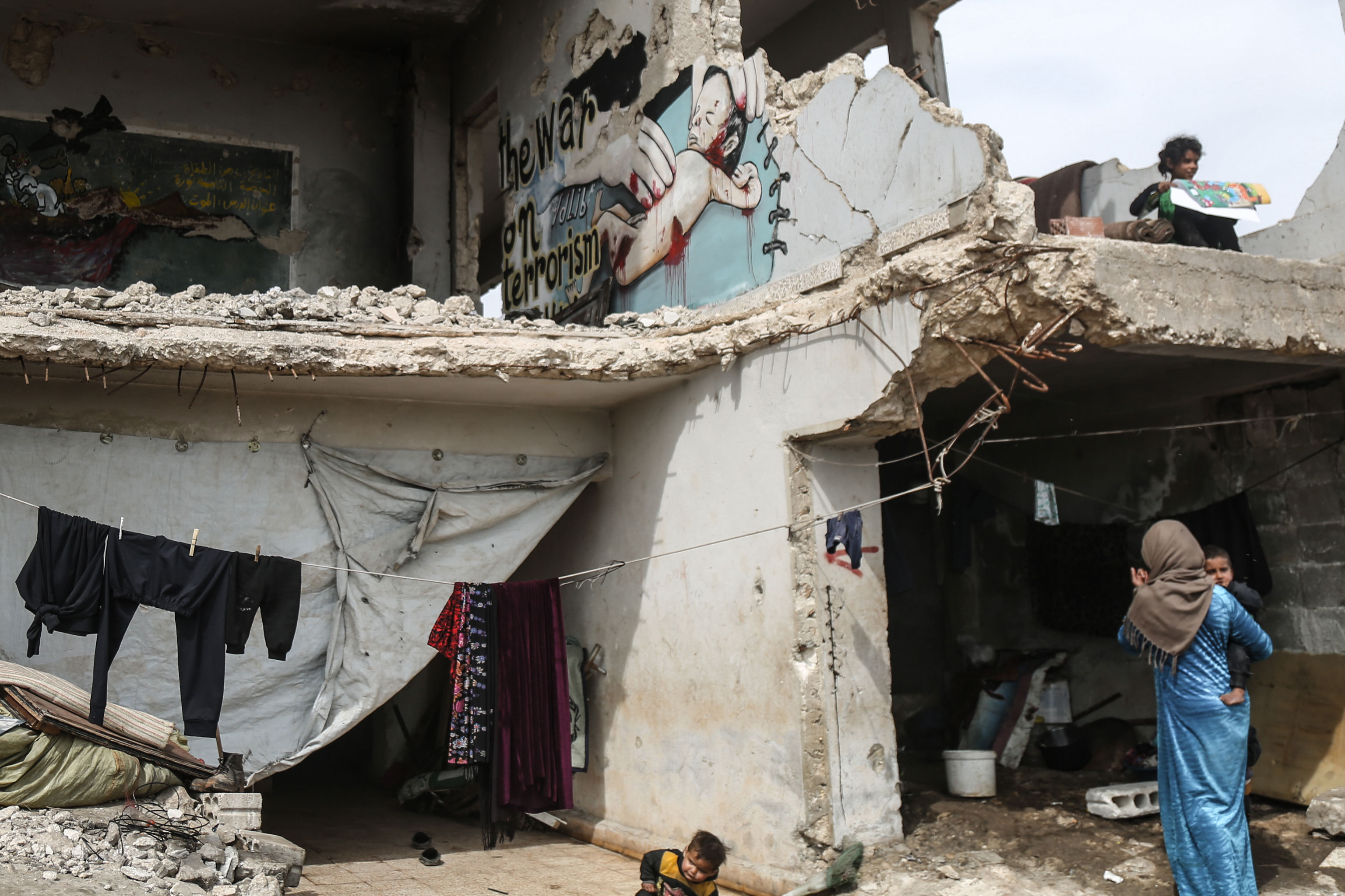 un bâtiment dont les murs ont été détruits abrite des familles démunies.