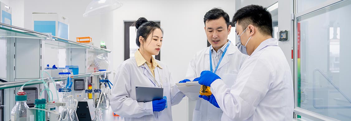 Scientists discussing the results of the experiment in laboratory holding a vial with glassware