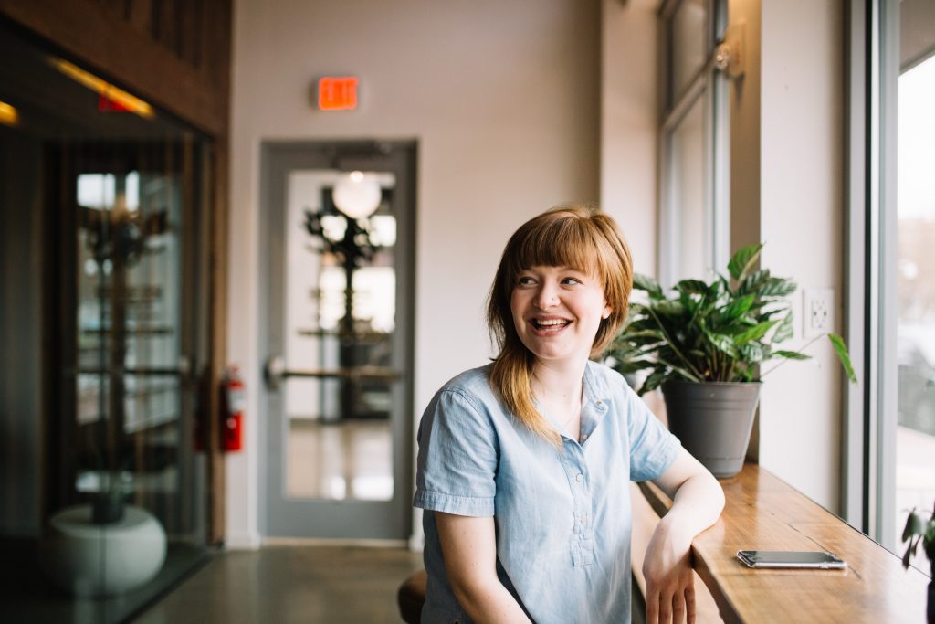 Woan smiling and lookin something in a cafe table.