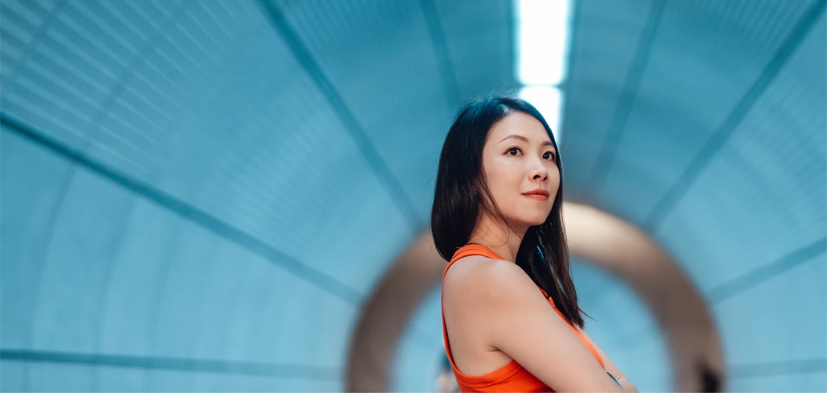 woman with long dark hair and orange blouse at the subway