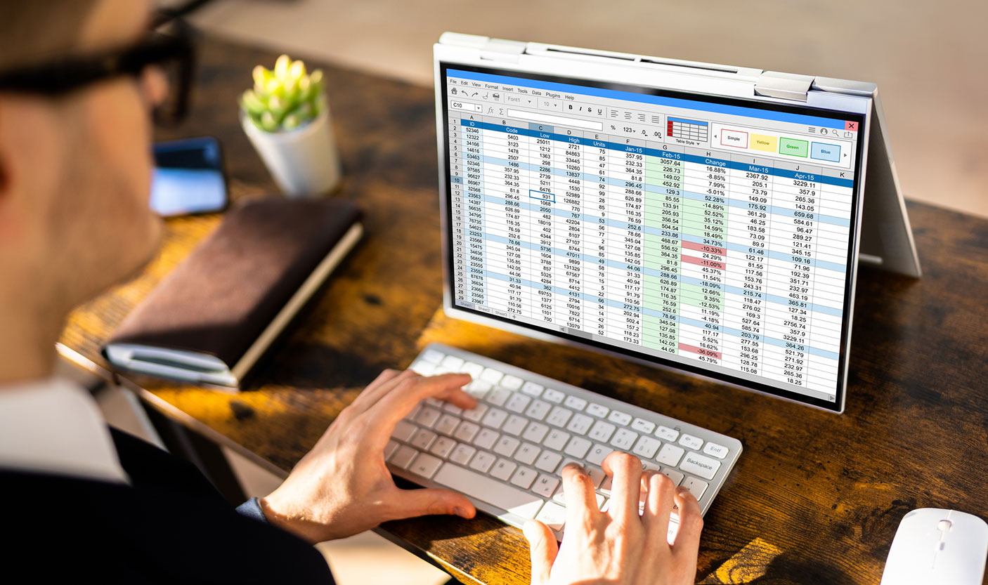 Person working at a computer with a spreadsheet of numbers on the screen